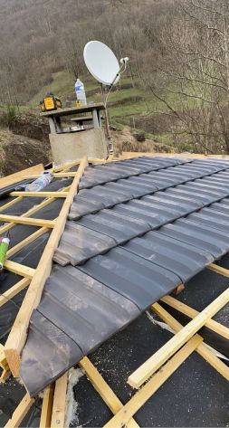 Couvreur posant des tuiles sur une toiture en Ariège